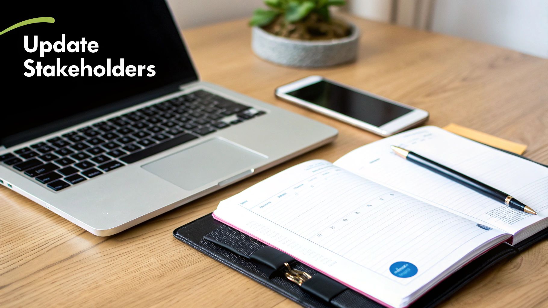 A laptop displaying 'Update Stakeholders', a smartphone, planner, and pen on a wooden desk.