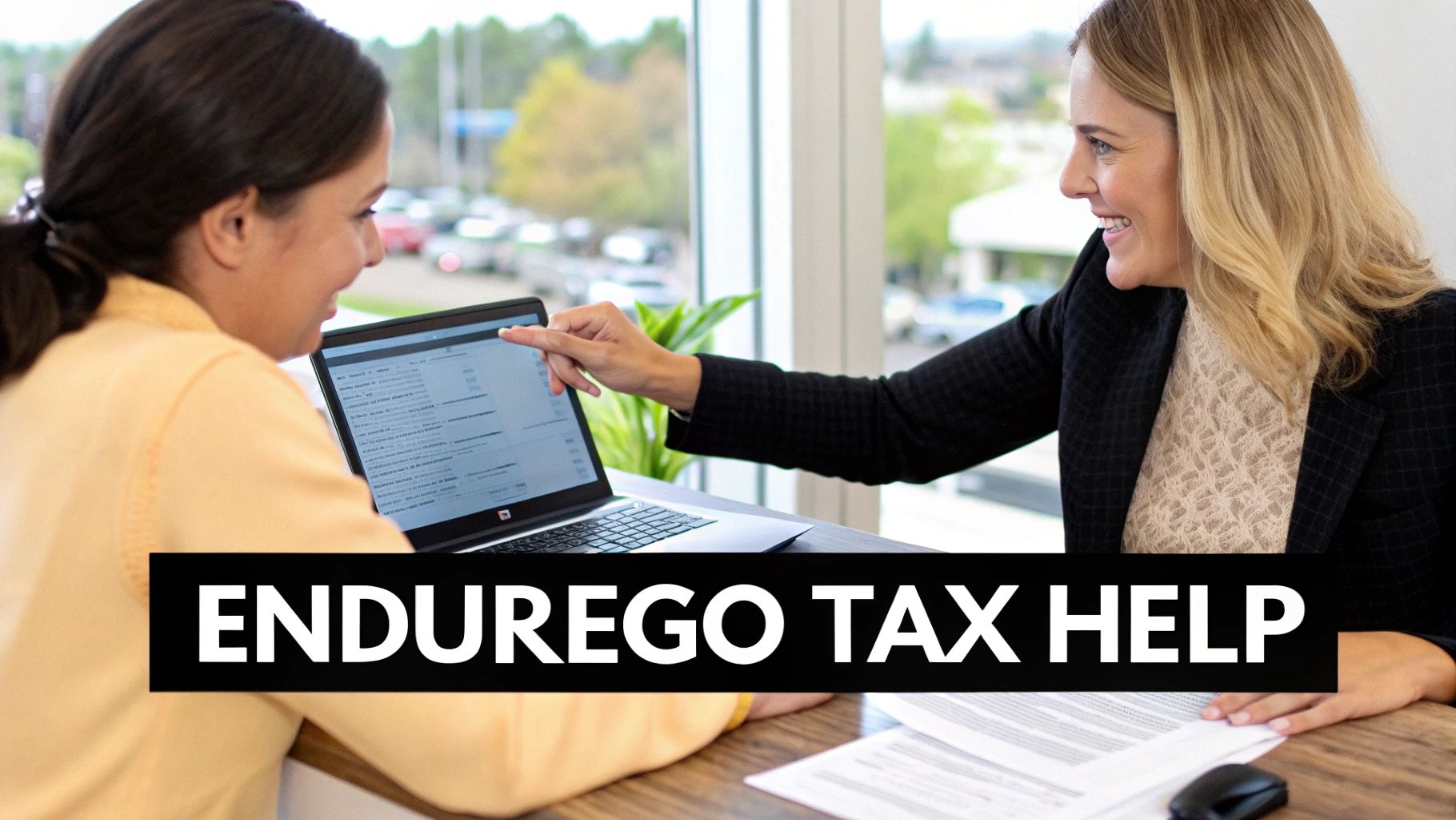 A tax professional points to a laptop screen while assisting a client with tax help.