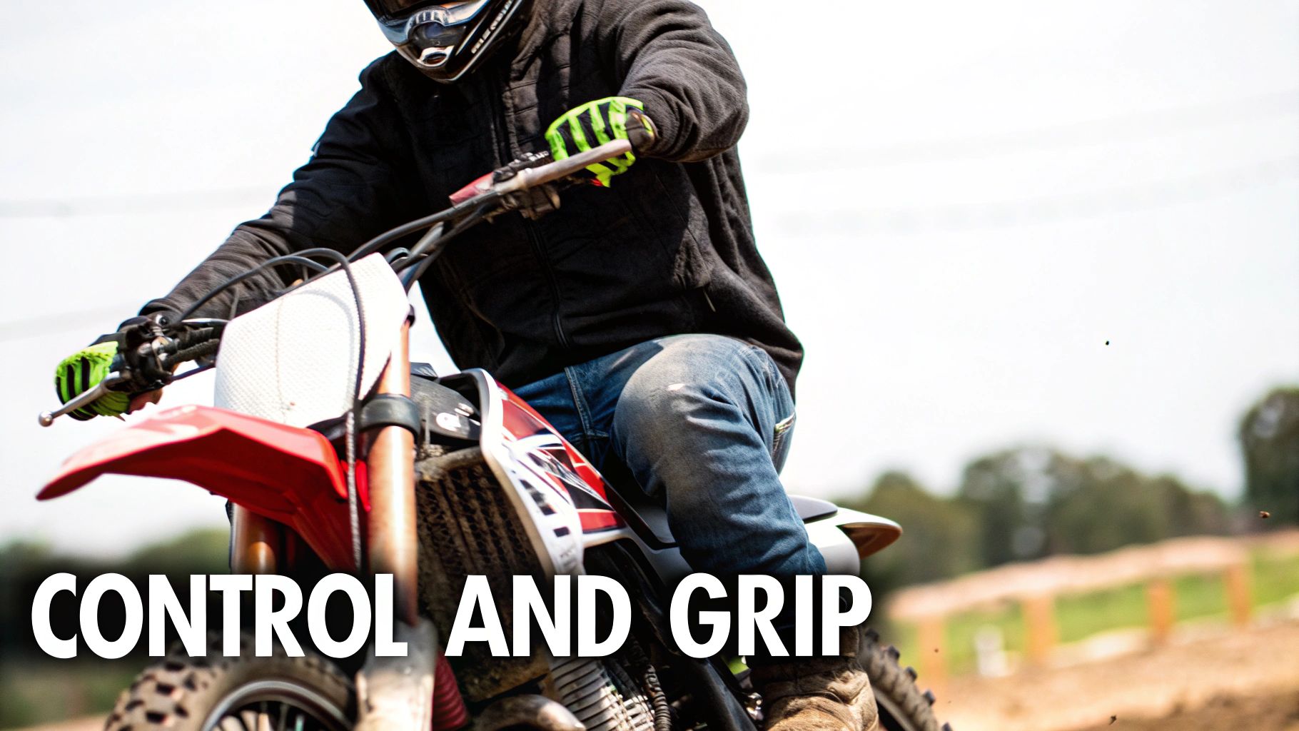 A rider gripping a dirt bike seat with their knees while navigating a turn on a dirt track.