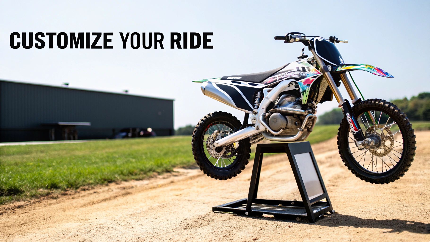 A dirt bike with vibrant custom moto graphics in a workshop setting.