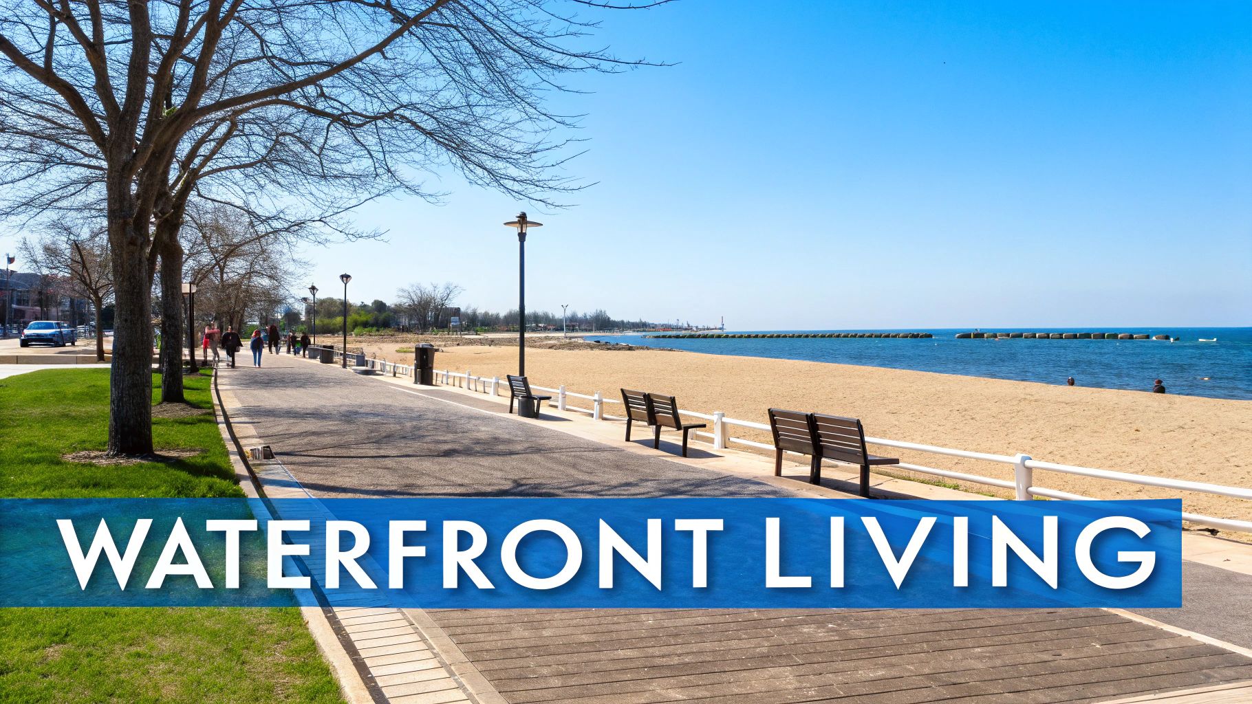 A scenic waterfront promenade on a sunny day with a sandy beach and calm blue water.