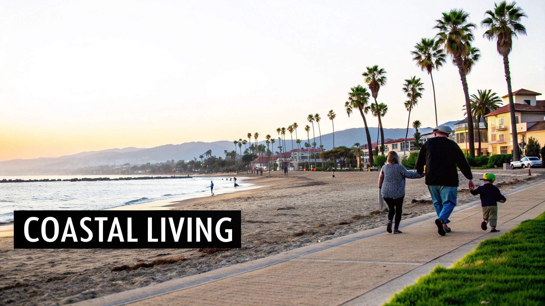A family walks along a paved path next to a sandy beach lined with palm trees at sunset.