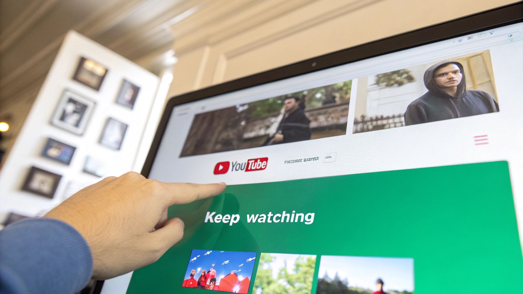 A person's hand pointing at a laptop screen showing the YouTube website and 'Keep watching' text.