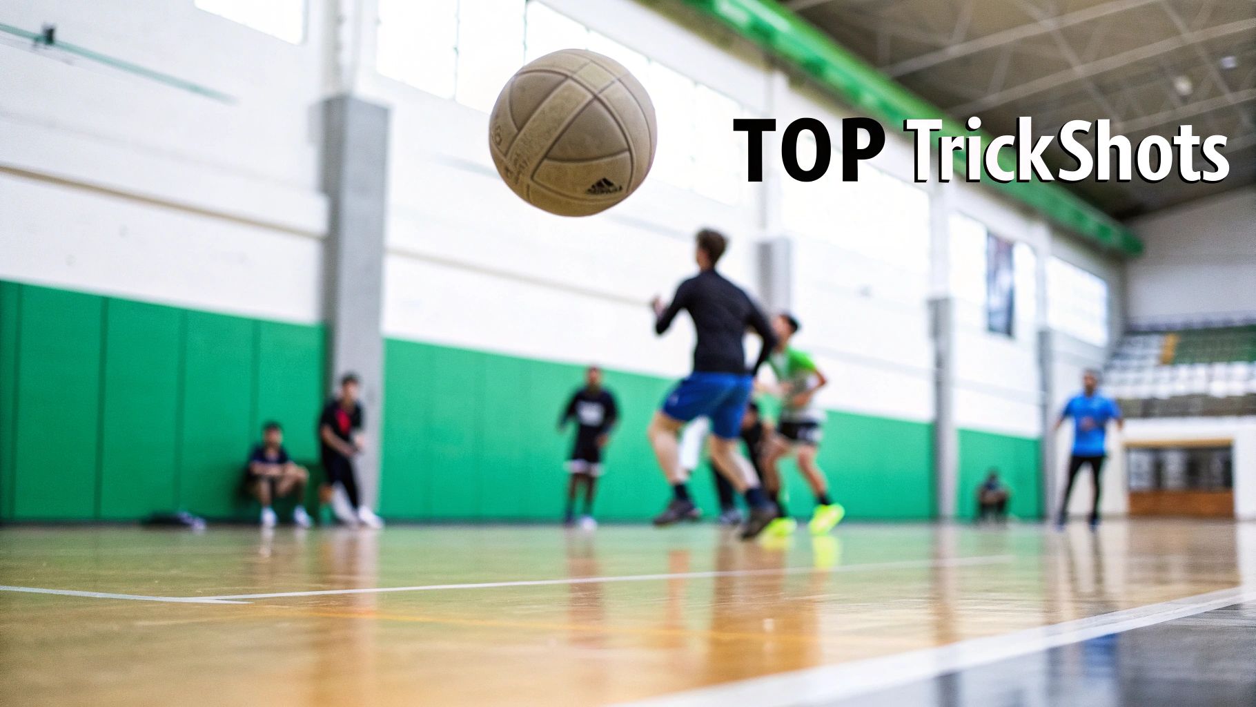 A soccer ball floats mid-air in a blurred indoor court with players and "TOP TrickShots" text.