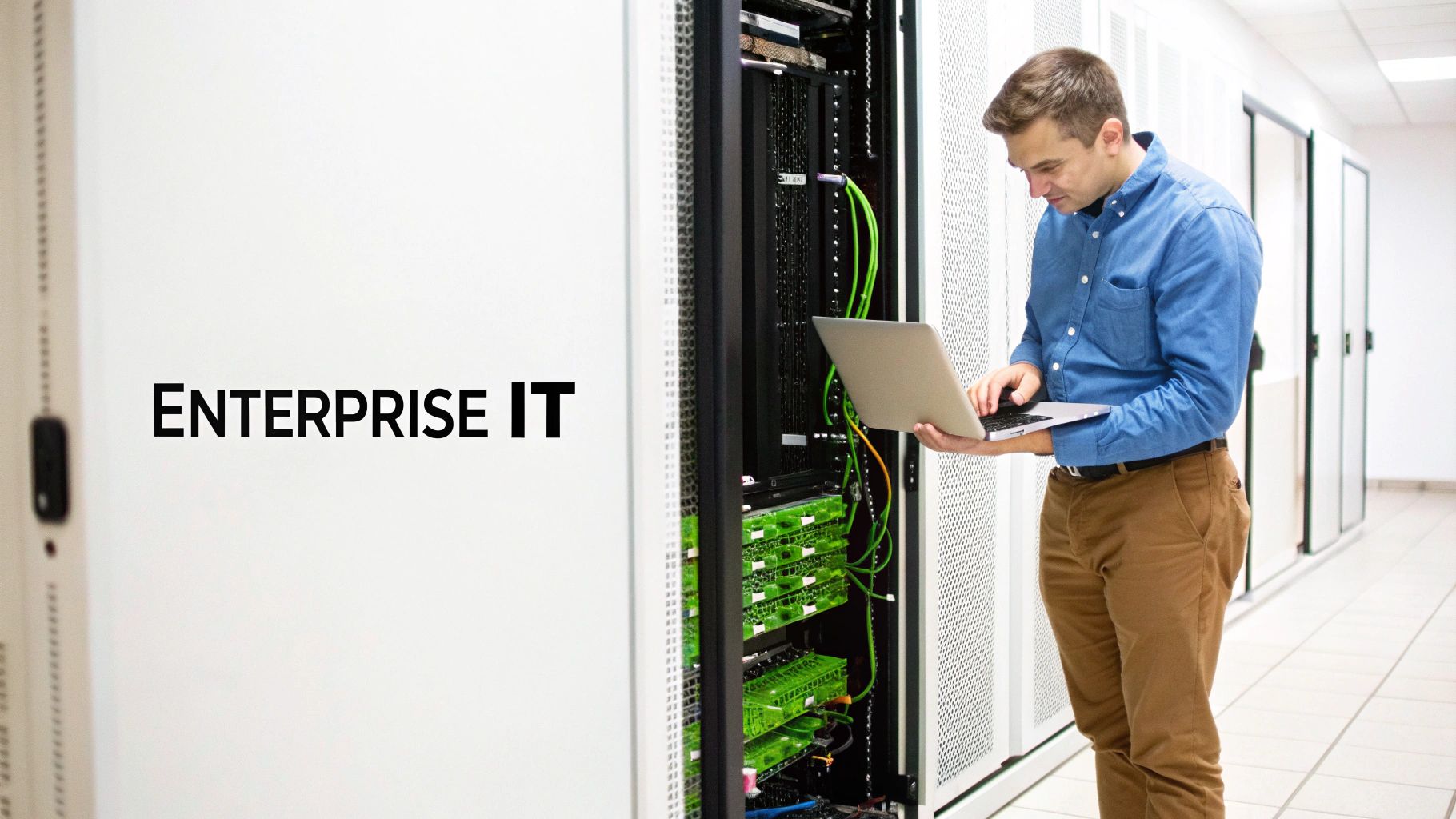An IT engineer uses a laptop to maintain server racks in a modern data center.