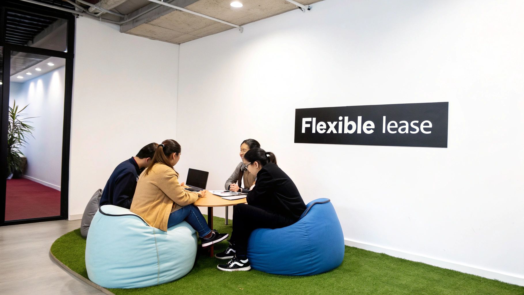 Four people sit on bean bag chairs around a table in a modern office with a 'Flexible lease' sign.