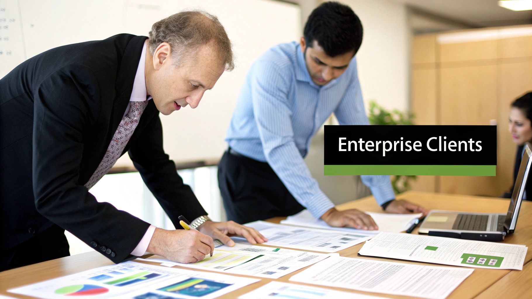 Three business professionals collaborating on documents, focusing on enterprise client strategies in an office.