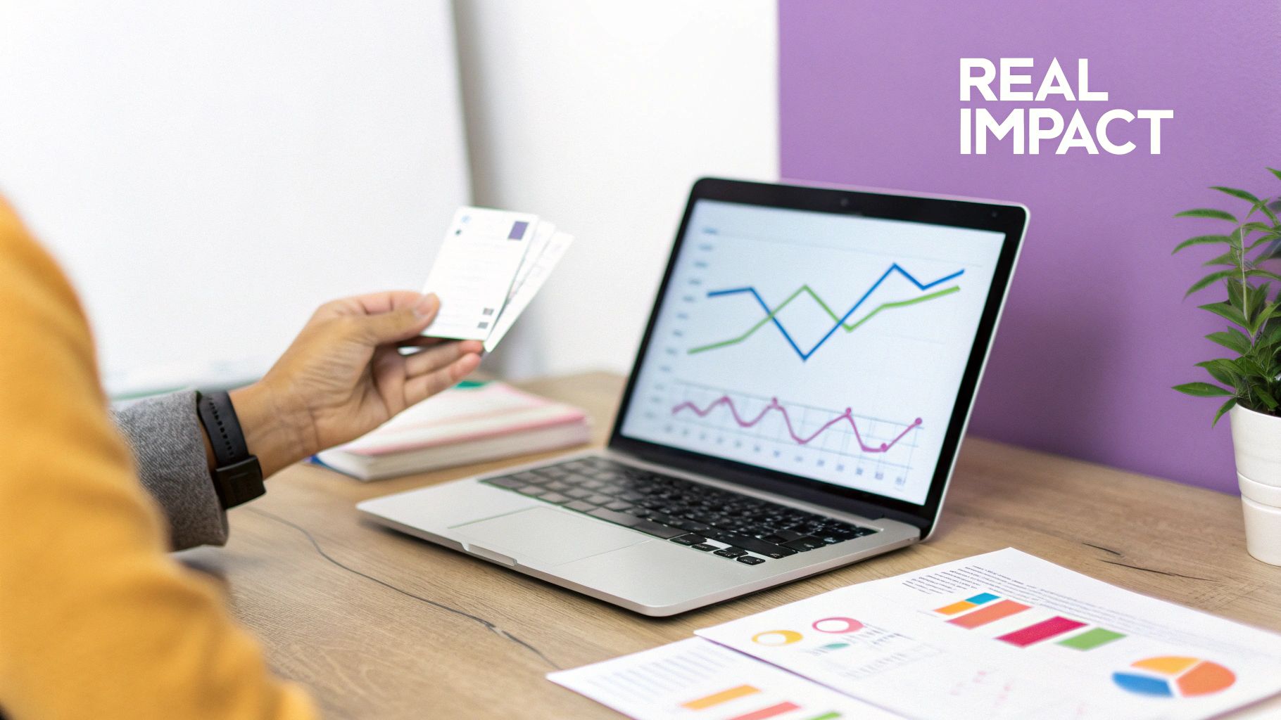 A person analyzes charts on a laptop and documents, holding cards, highlighting data analysis for real impact.