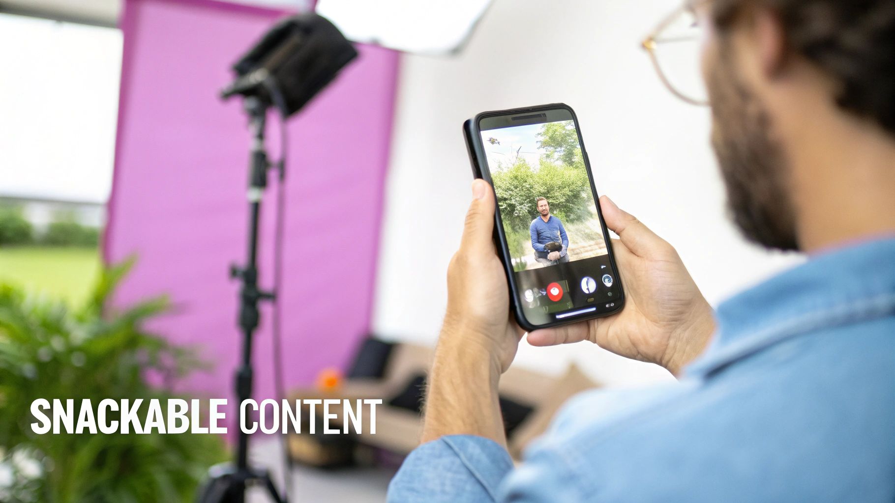 Person filming video with a smartphone in a studio setting with a purple backdrop for content creation.