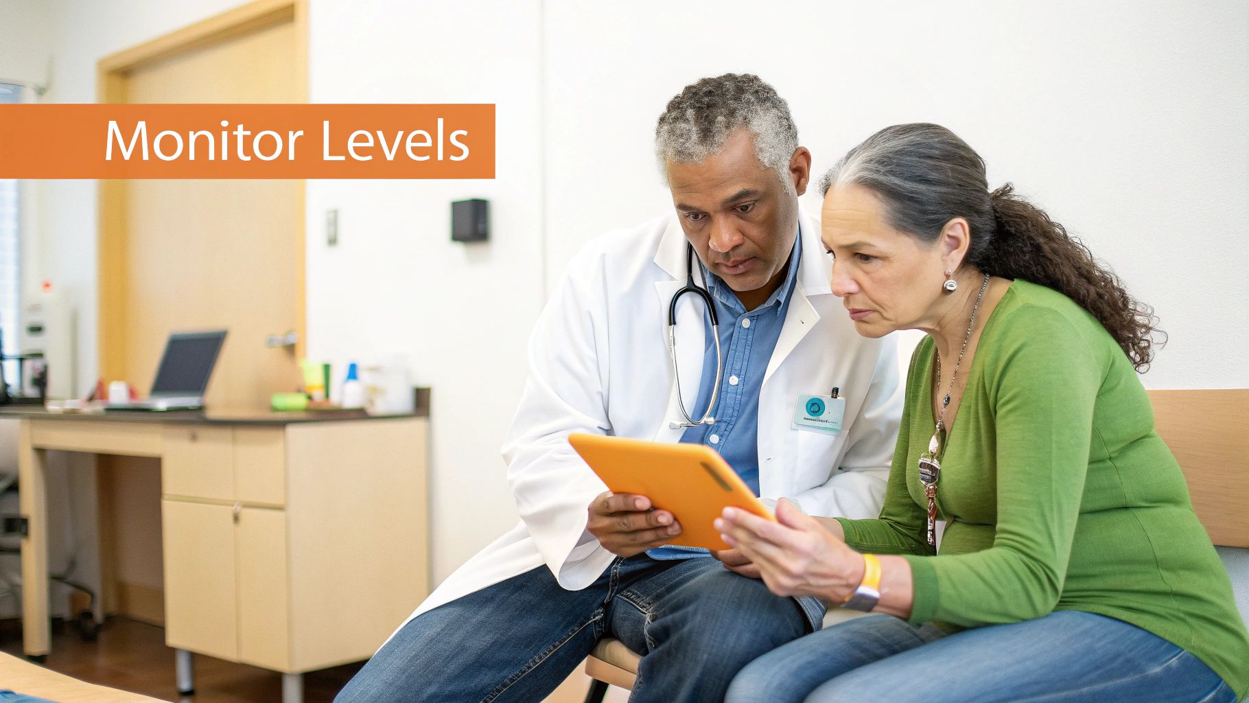 A male doctor and a female patient review information together on a tablet in a clinic.