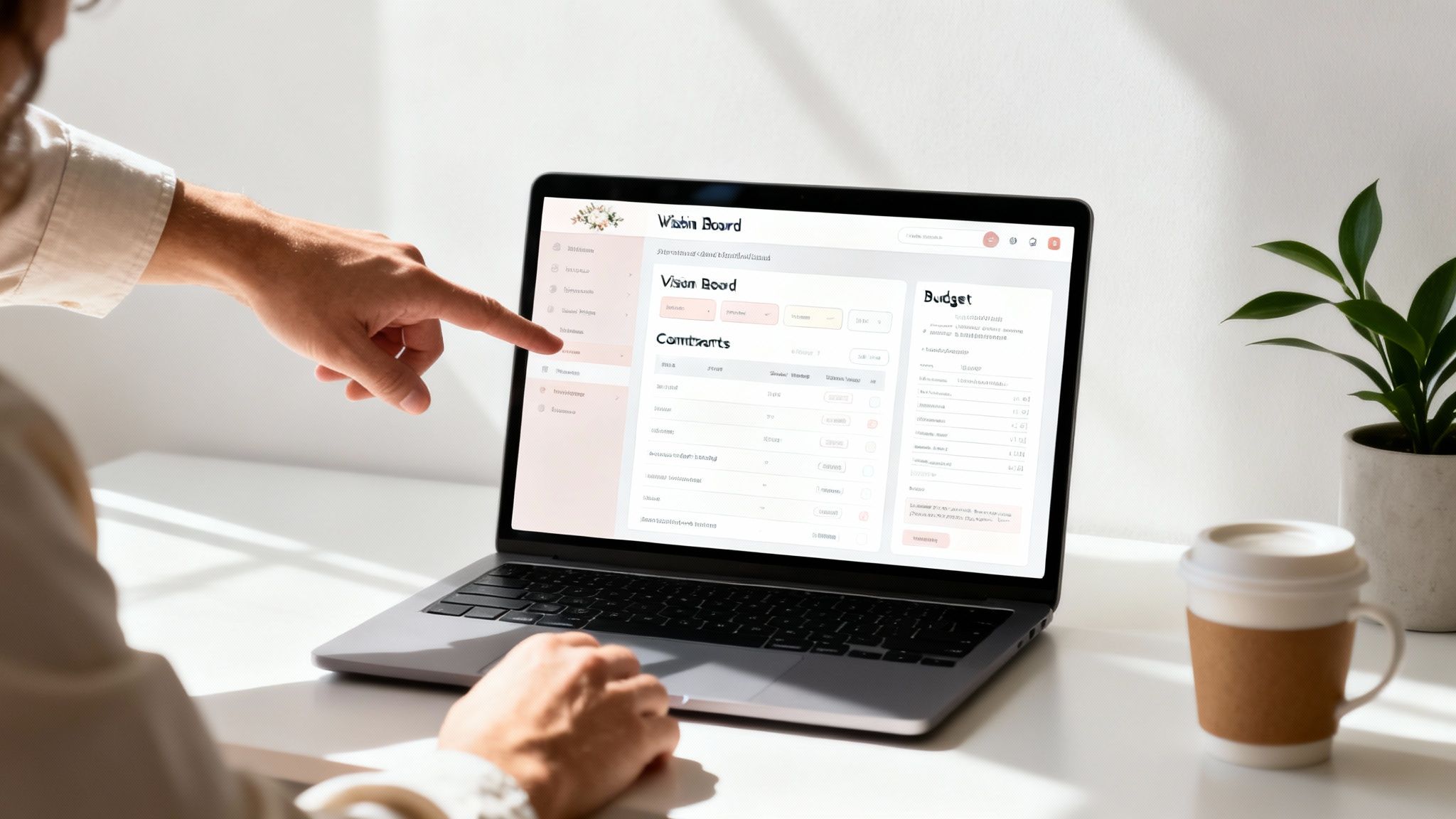 A person's hand points to a laptop screen displaying a 'Vision Board' and 'Budget' interface.
