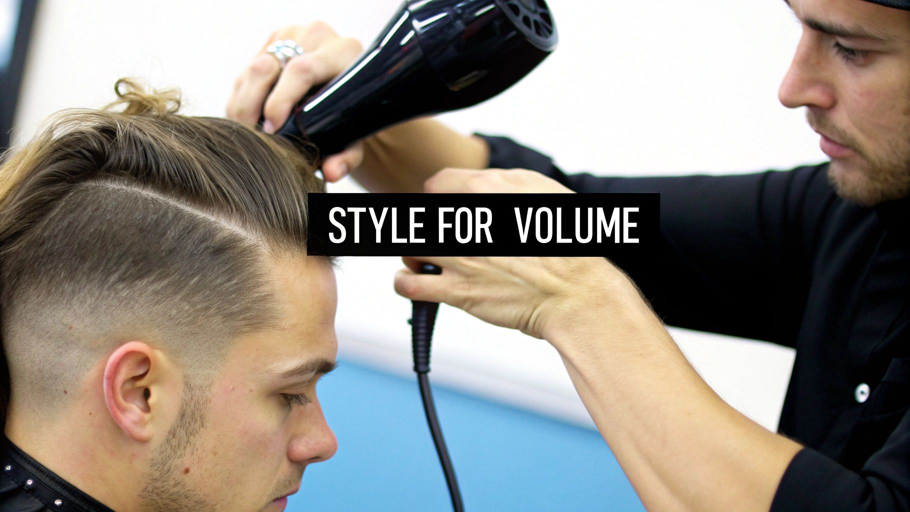 A barber blow-dries a man's hair to add volume, showcasing a modern hairstyle.