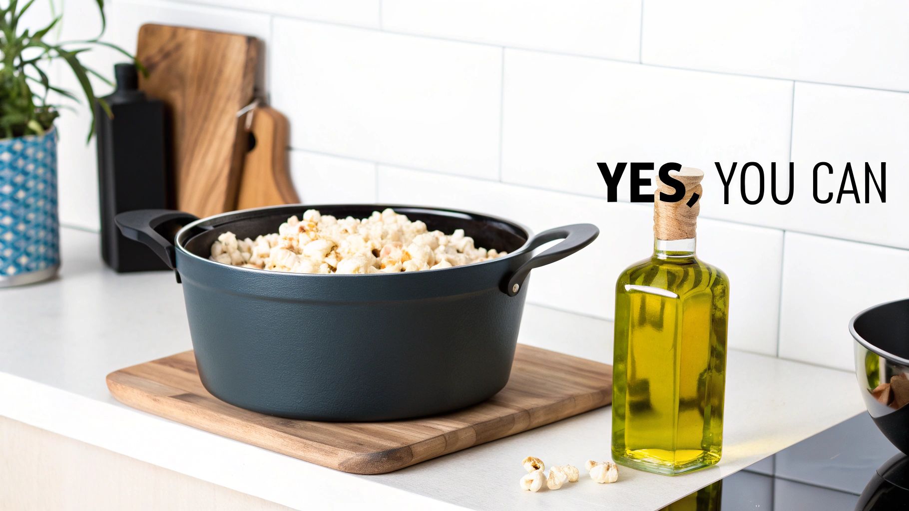 A pot of popcorn on a wooden board next to olive oil in a bright kitchen, with text 'YES, YOU CAN'.