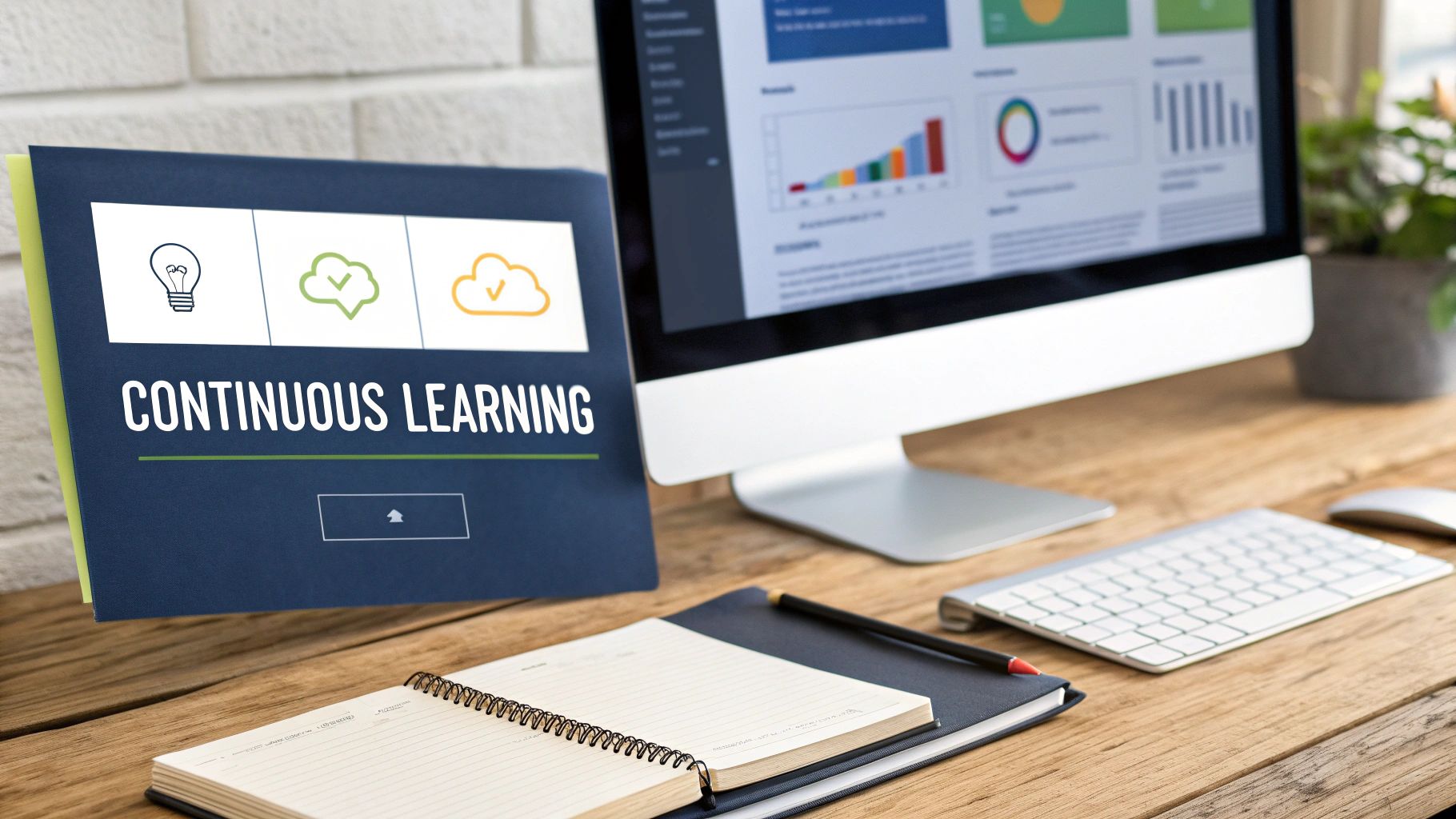 Modern office desk with a computer displaying analytics, a 'Continuous Learning' document, and stationery.