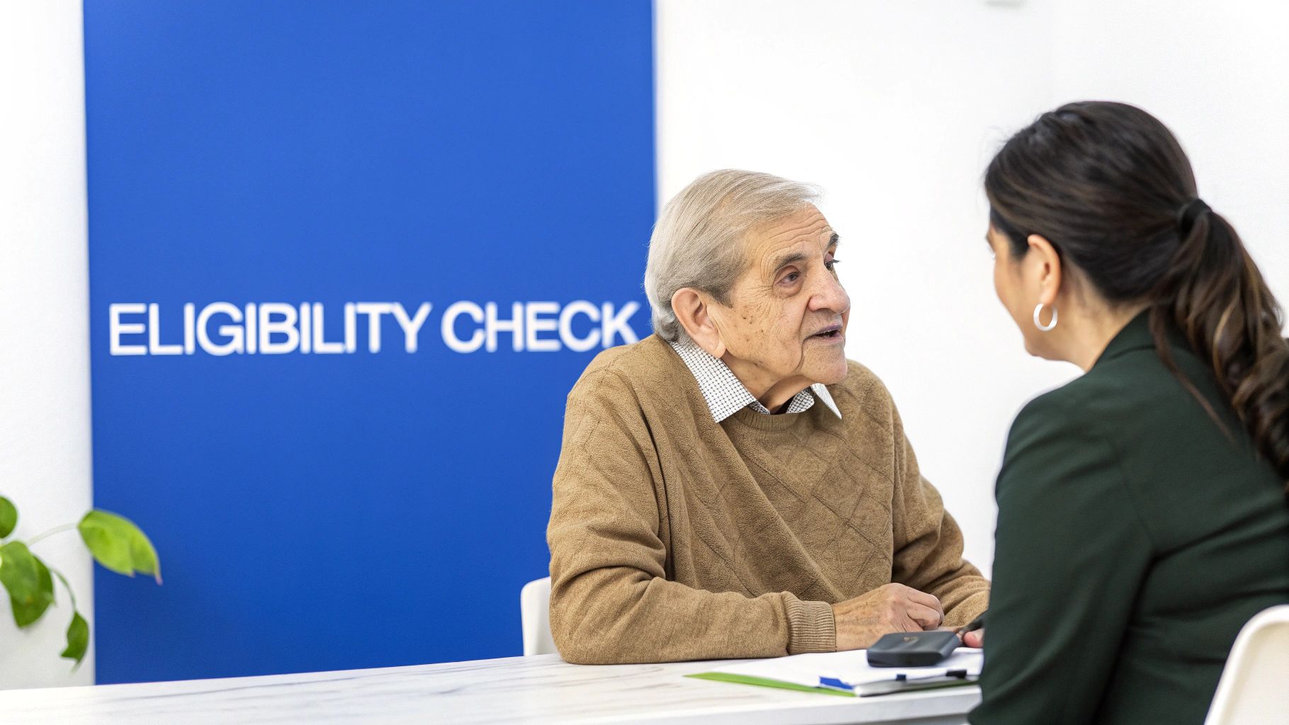 A senior woman and her caregiver smiling and reviewing paperwork together at a kitchen table.