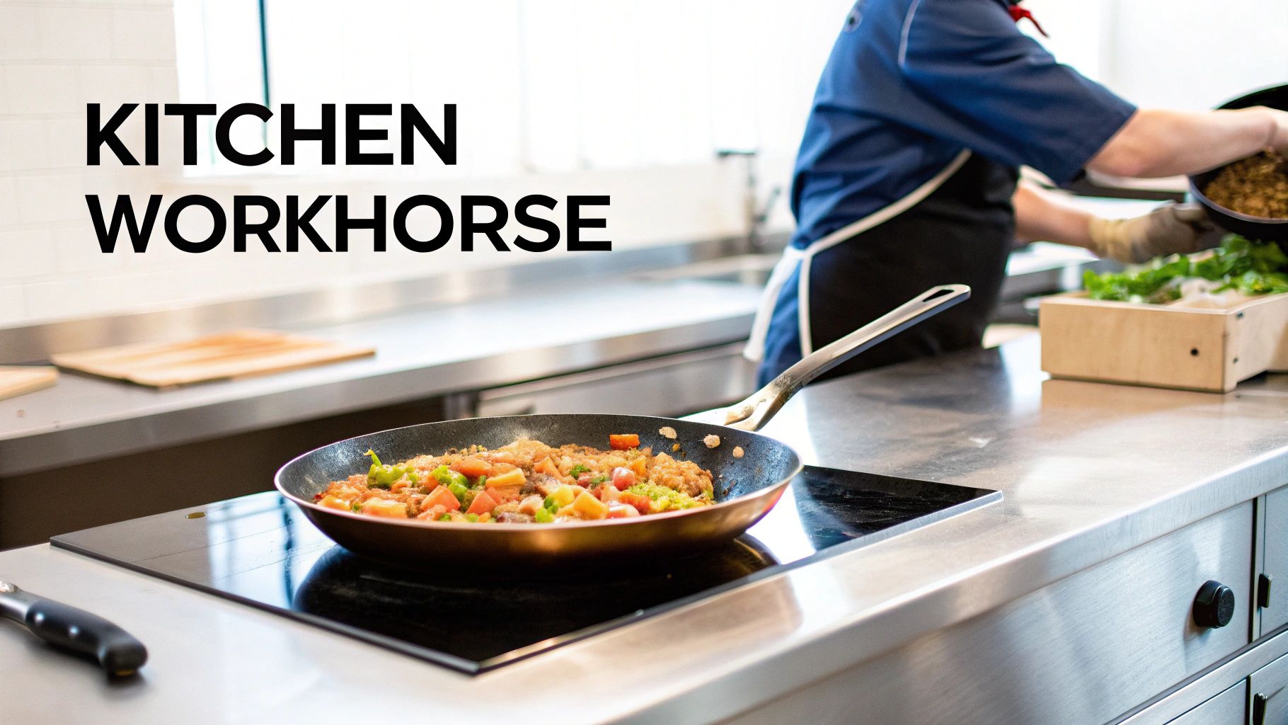 A chef in a commercial kitchen preparing food with a skillet on an induction cooktop.