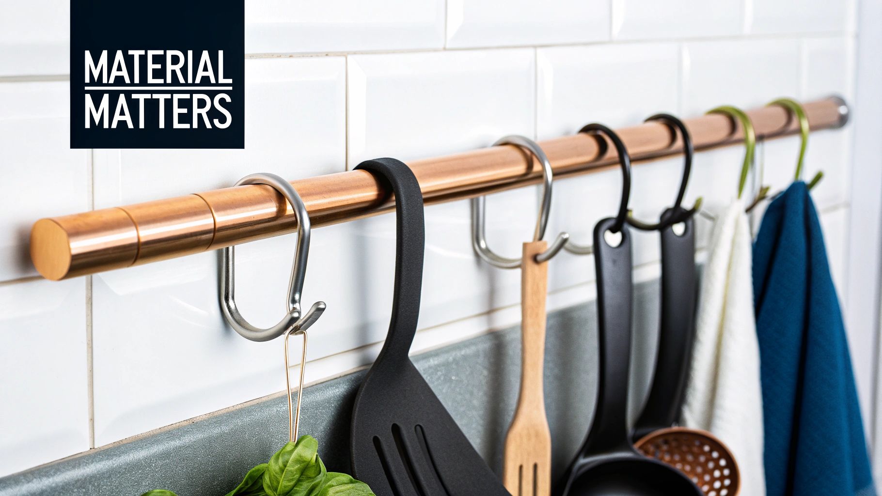 A copper kitchen rod with S-hooks holding various kitchen utensils and towels against a white tiled wall.