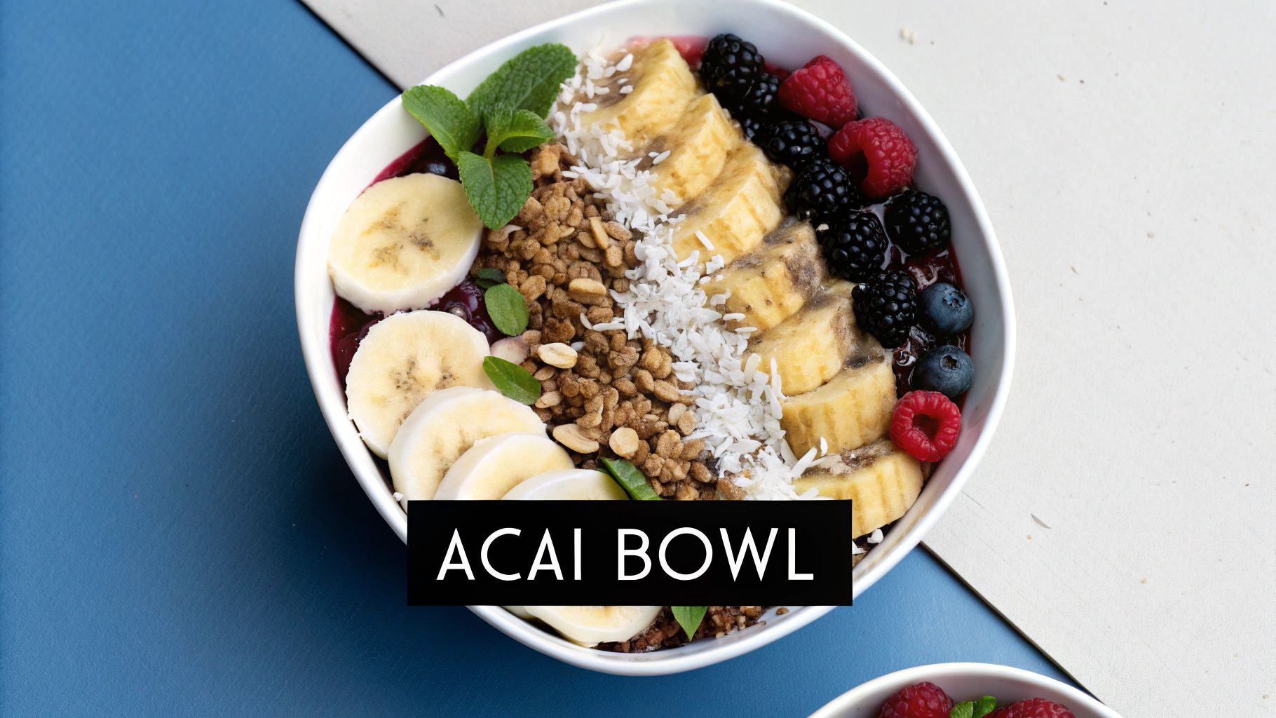 A vibrant acai bowl topped with sliced bananas, mixed berries, granola, and shredded coconut.