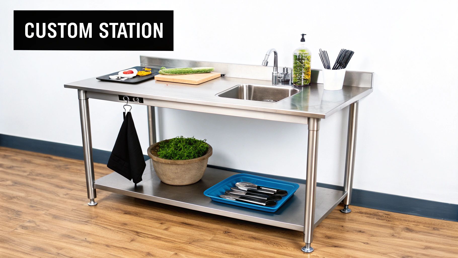 A stainless steel kitchen prep table with an integrated sink, cutting board, and kitchen accessories.
