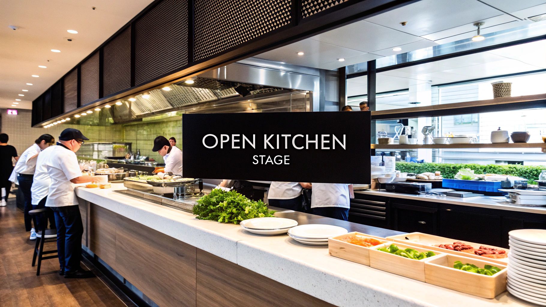 Chefs prepare food in a modern open kitchen with a counter display of fresh ingredients.