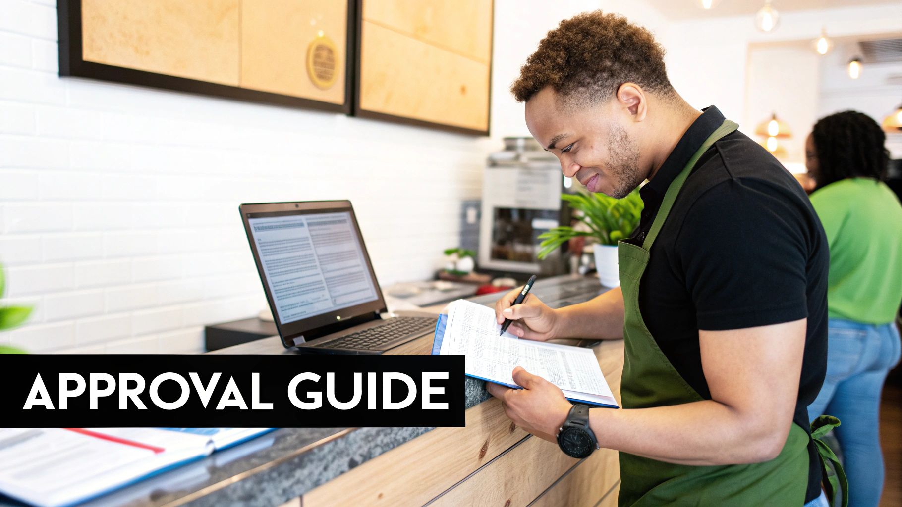 Young man in a green apron diligently writing on an approval guide document in a cafe.
