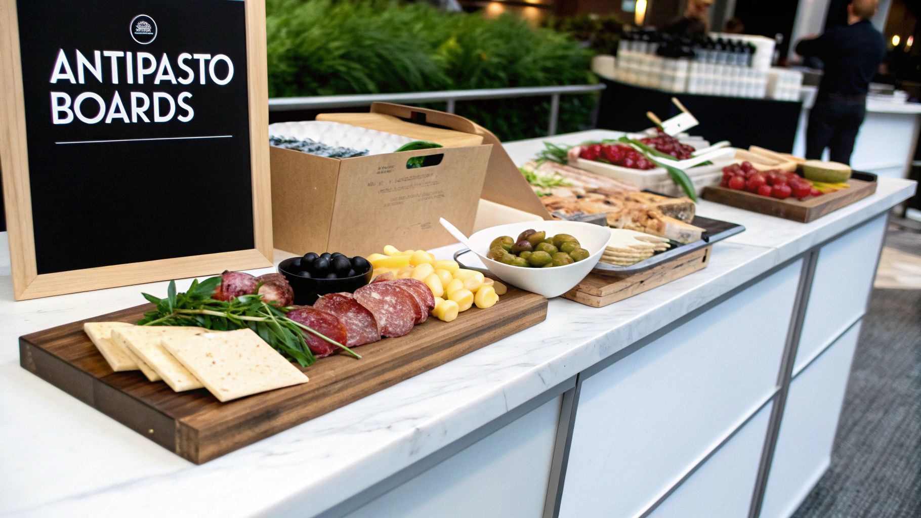 A vibrant buffet featuring antipasto boards with assorted meats, cheeses, olives, and crackers, highlighted by a blackboard sign.