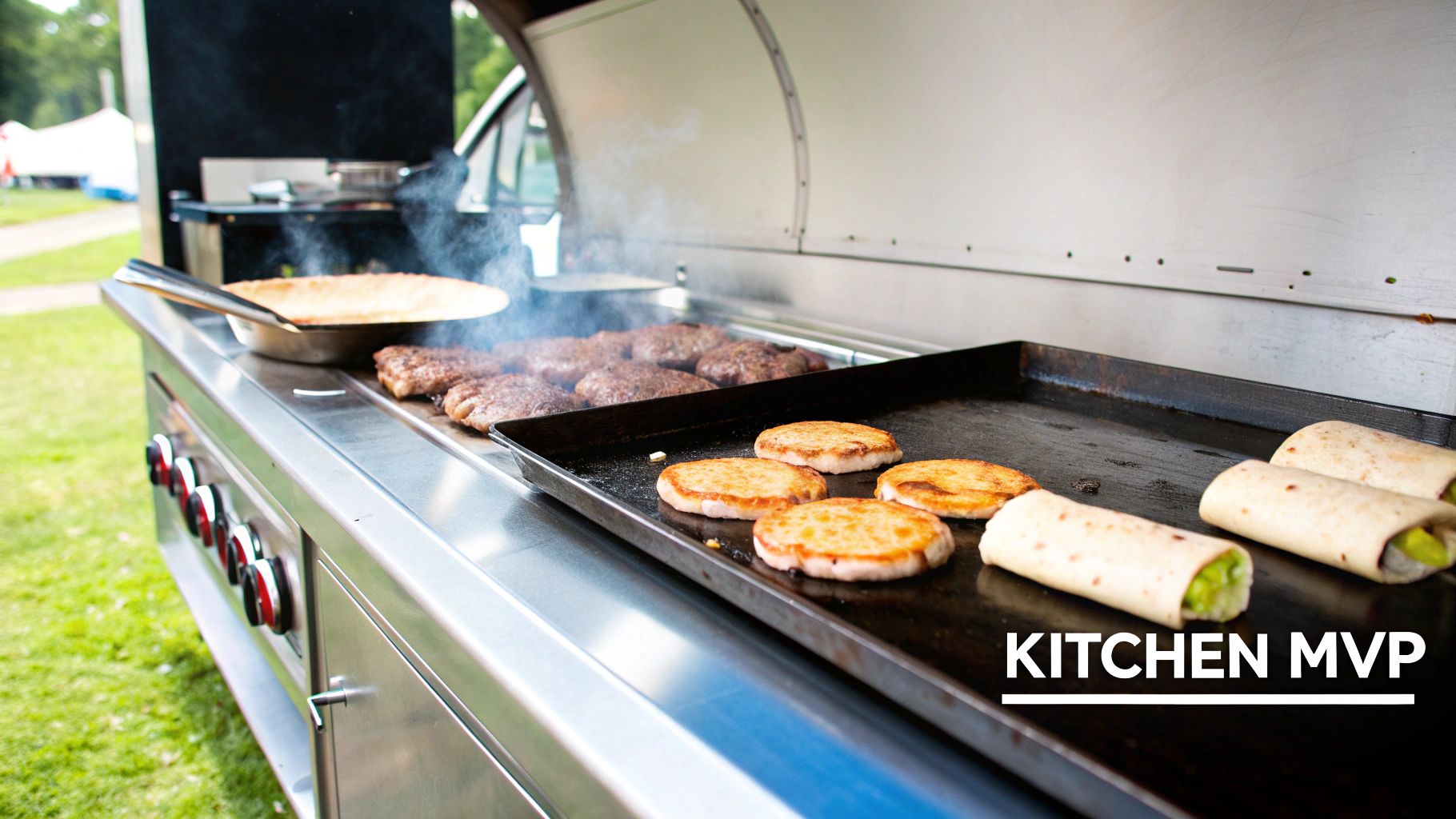 Close-up of a food truck's stainless steel griddle cooking burgers, wraps, and round patties.