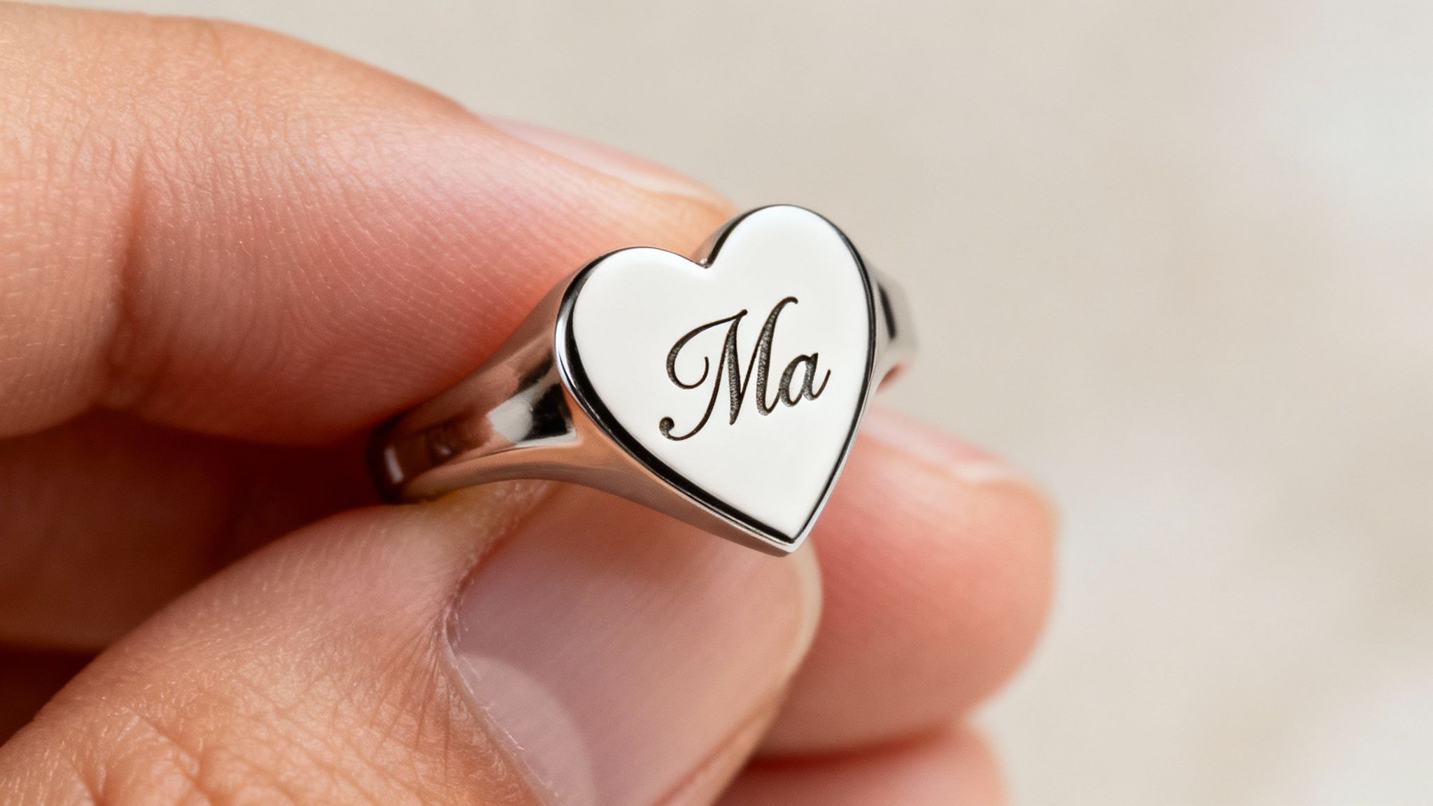Close-up of an engraving tool carefully carving initials into a heart-shaped ring.
