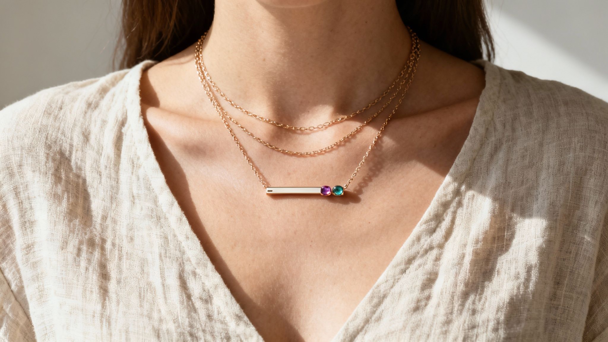 Woman wearing a layered bar necklace with birthstones, paired with a v-neck top.