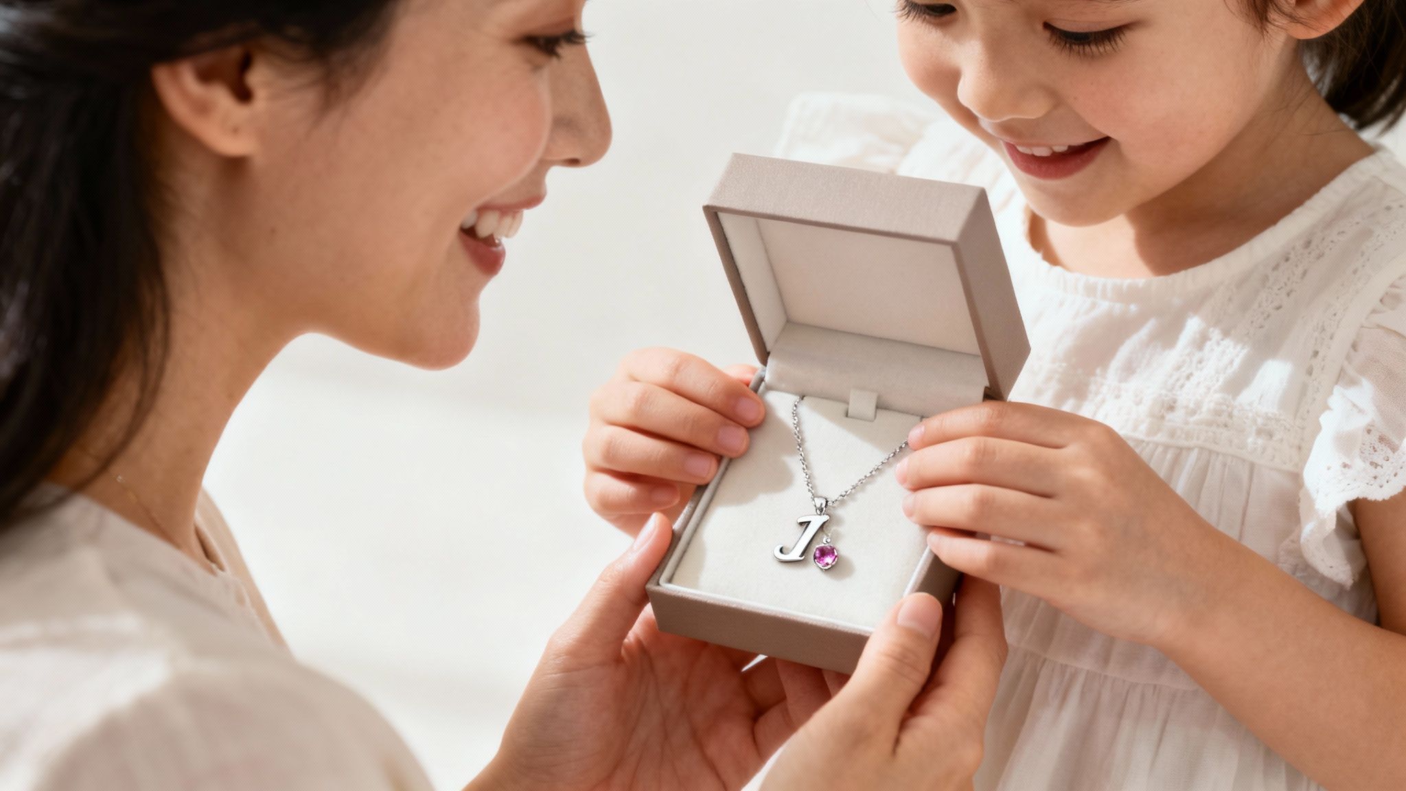 Mother and daughter admiring personalized initial necklace with gemstone in gift box