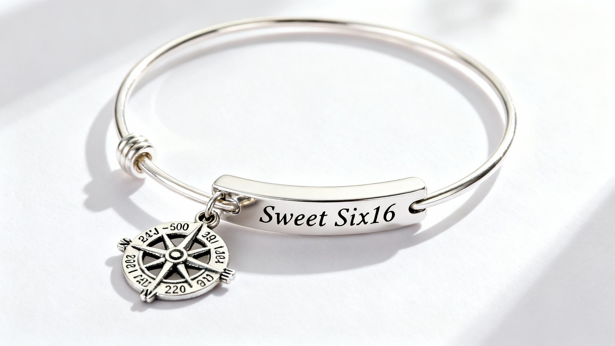 A close-up of a personalized sweet sixteen bracelet with charms and engravings.