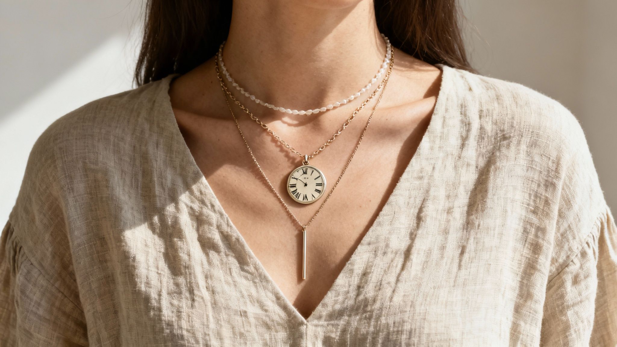 A woman layers her gold roman numeral necklace with other delicate chains, creating a stylish look.