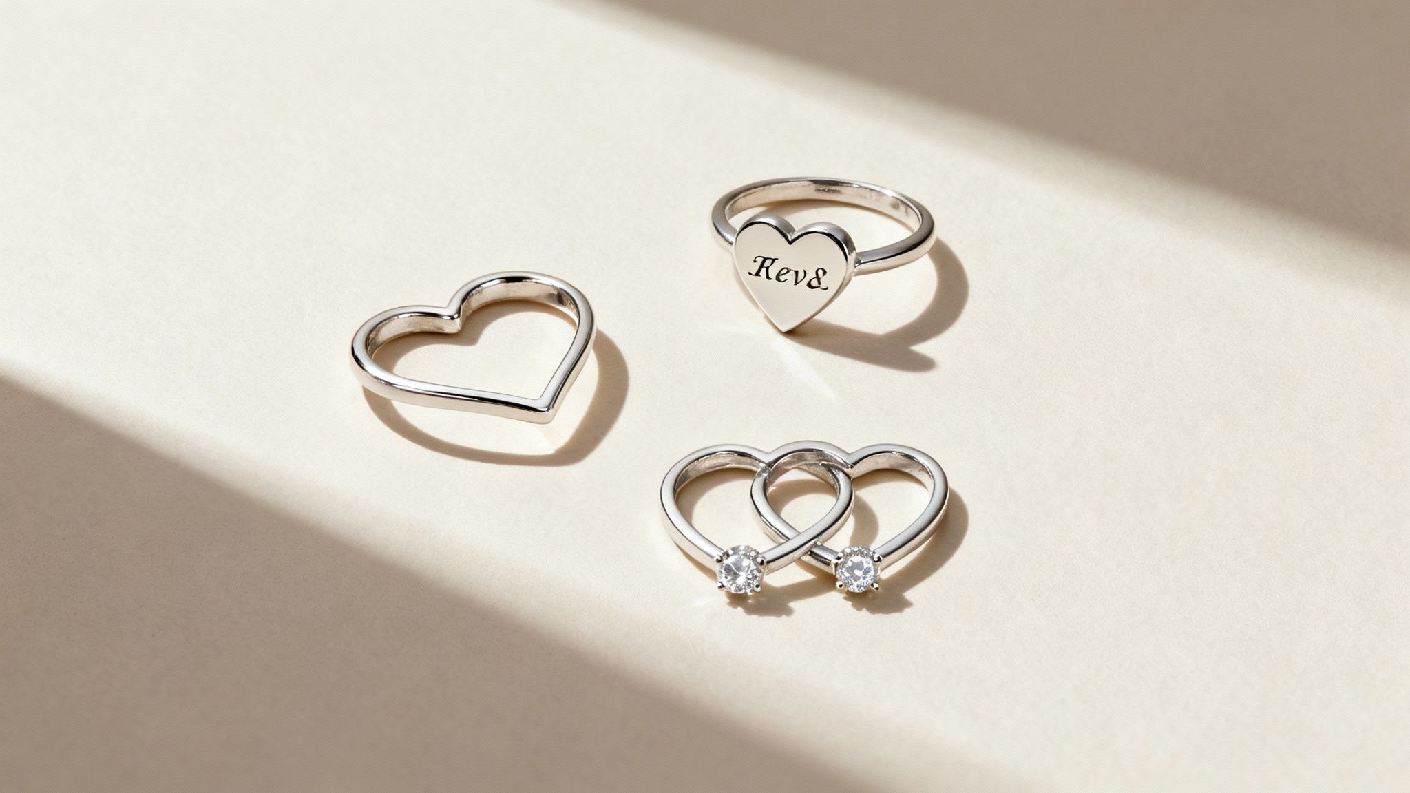 A delicate heart ring with initials engraved on it, held in someone's hand.