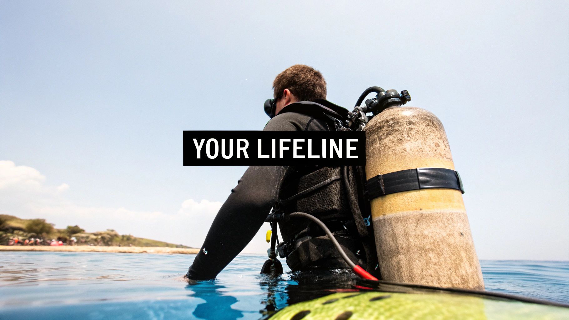 A diver in a wetsuit with an oxygen tank on their back enters the ocean, looking at the shore.