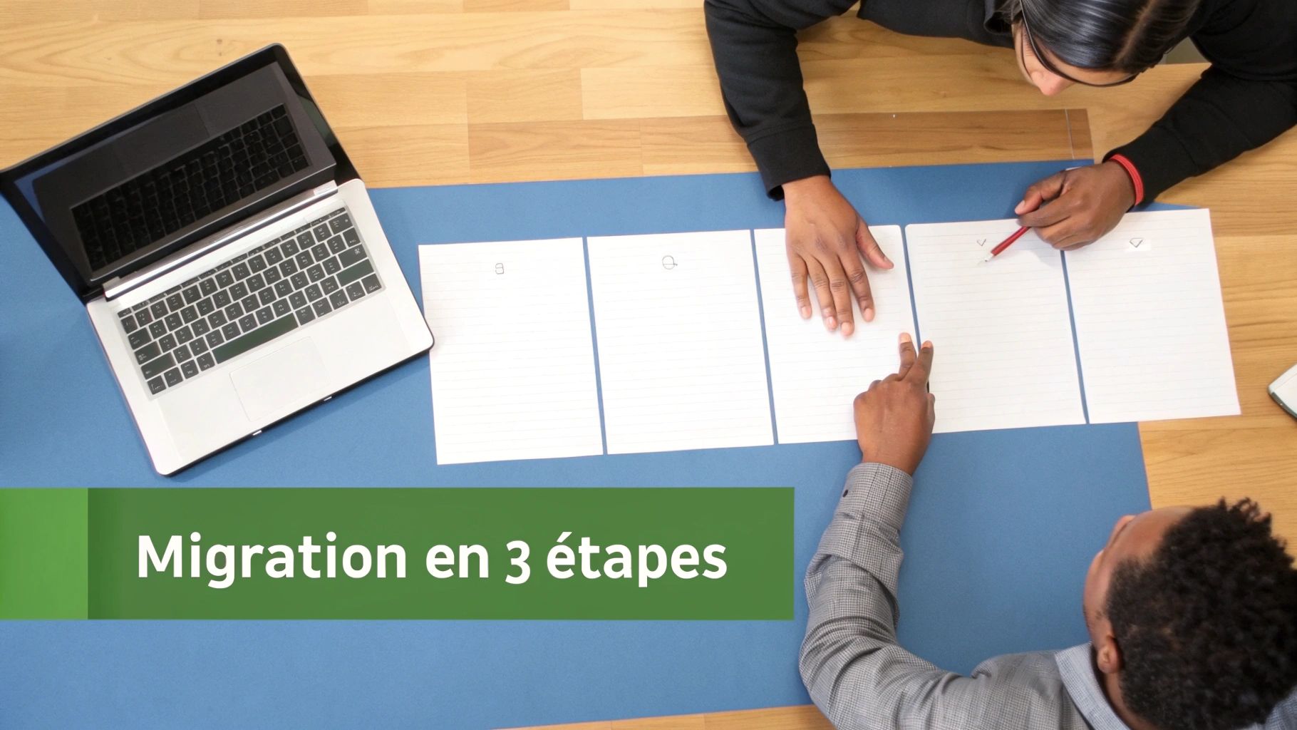 Vue aérienne de deux personnes planifiant une migration en 3 étapes avec des documents et un ordinateur portable.