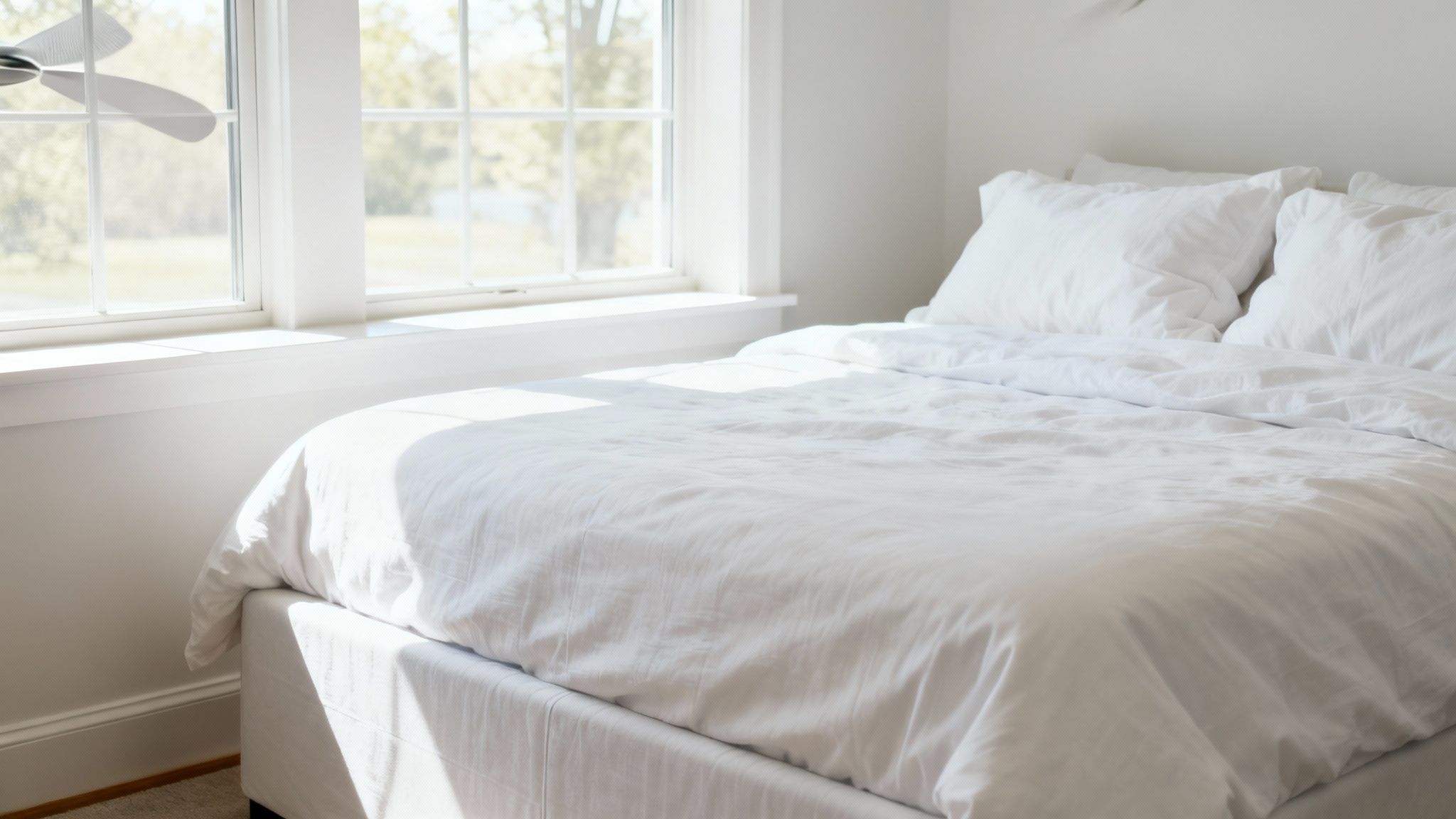 A cozy, clean bedroom with a freshly made bed and sunlight streaming through the window.