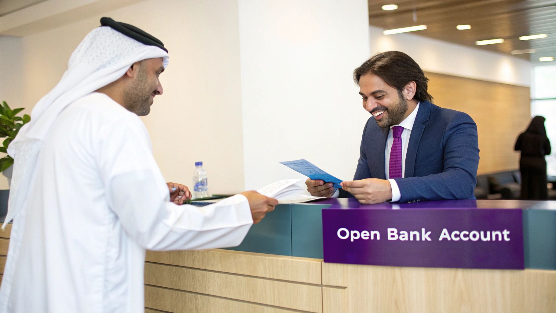 A man in traditional attire hands documents to a smiling bank employee at a counter with an "Open Bank Account" sign.
