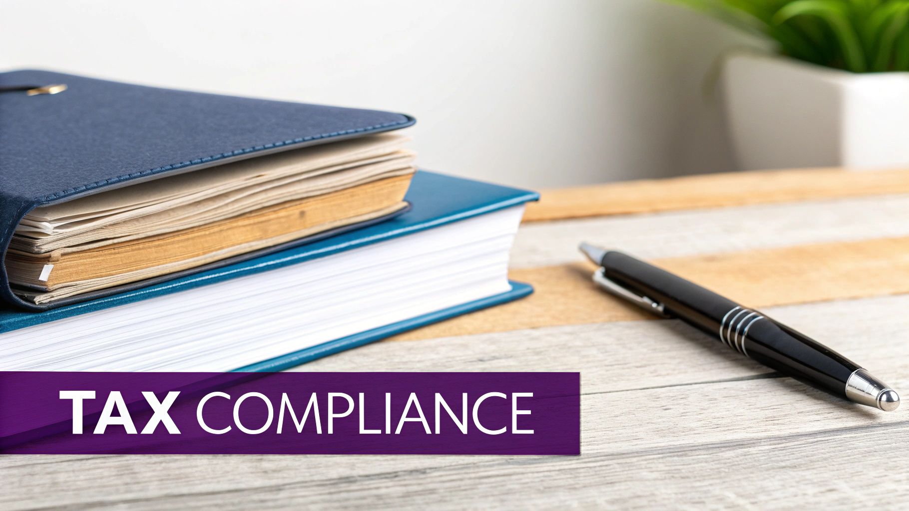 Two books and a pen on a wooden desk, with a 'TAX COMPLIANCE' banner.