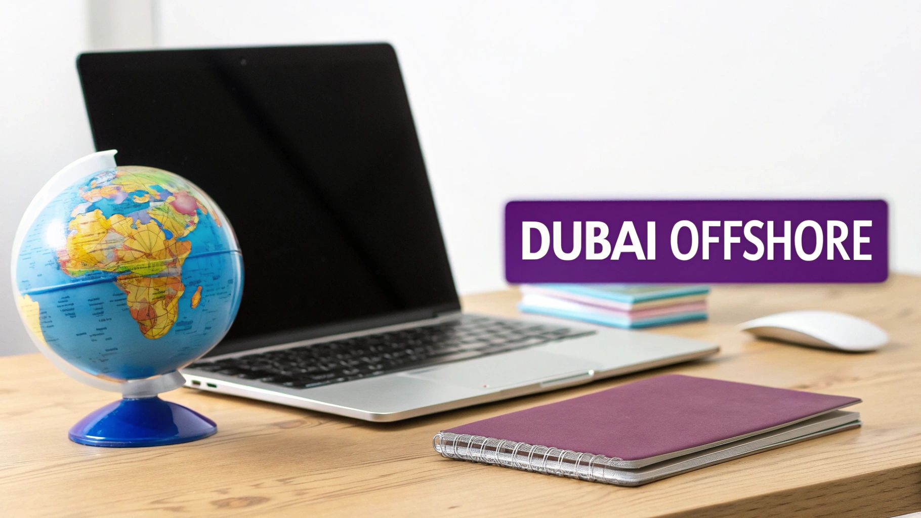 A work setup with a laptop, globe, and a purple sign saying "DUBAI OFFSHORE" on a wooden table.