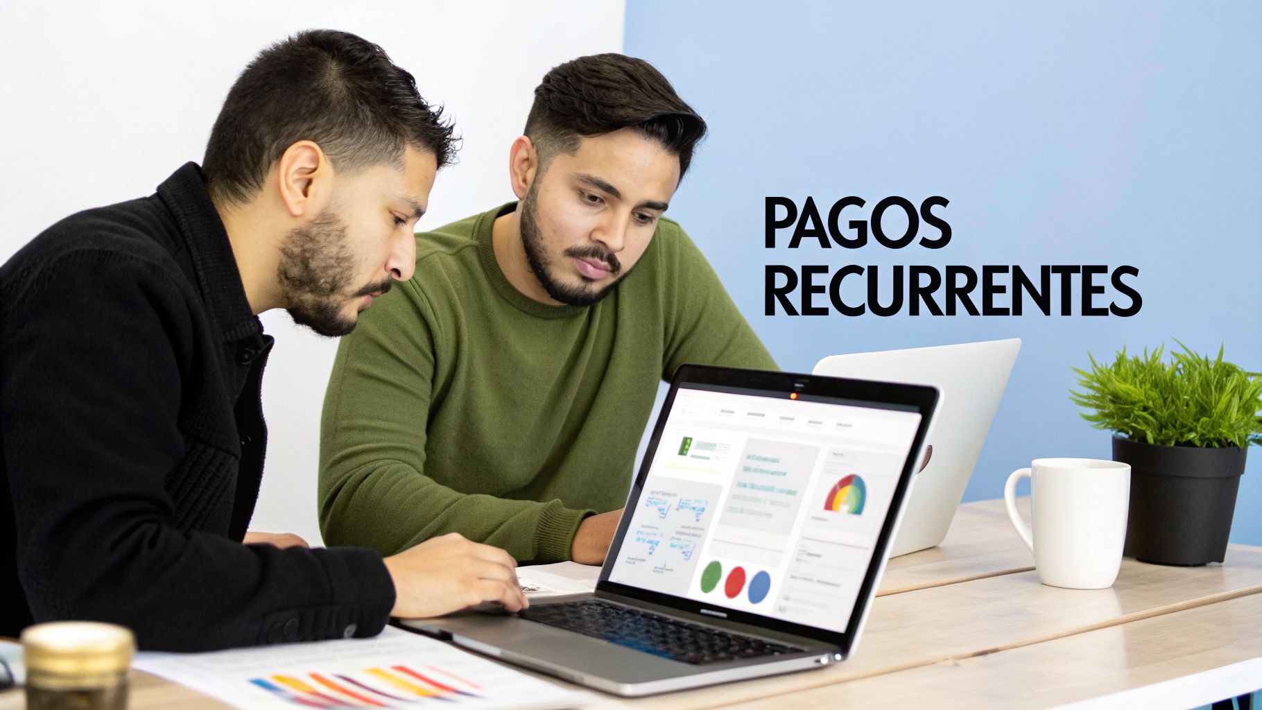 Dos hombres colaboran en laptops en un escritorio con gráficos y el texto "Pagos Recurrentes" en la pared.