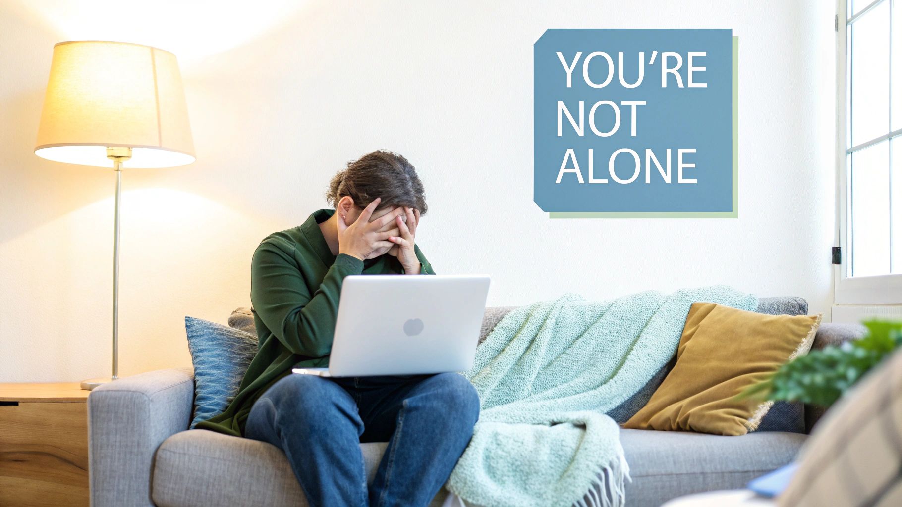 A person appears distressed, covering their face while sitting on a couch with a laptop, a 'YOU'RE NOT ALONE' sign on the wall.