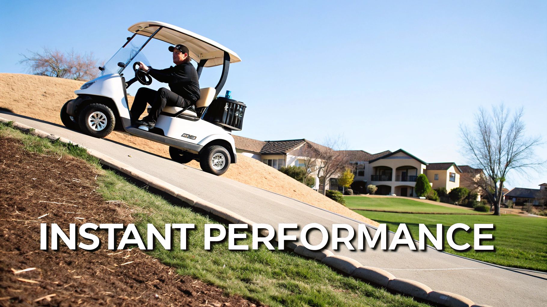 A man drives a white golf cart uphill on a paved path against a clear blue sky.