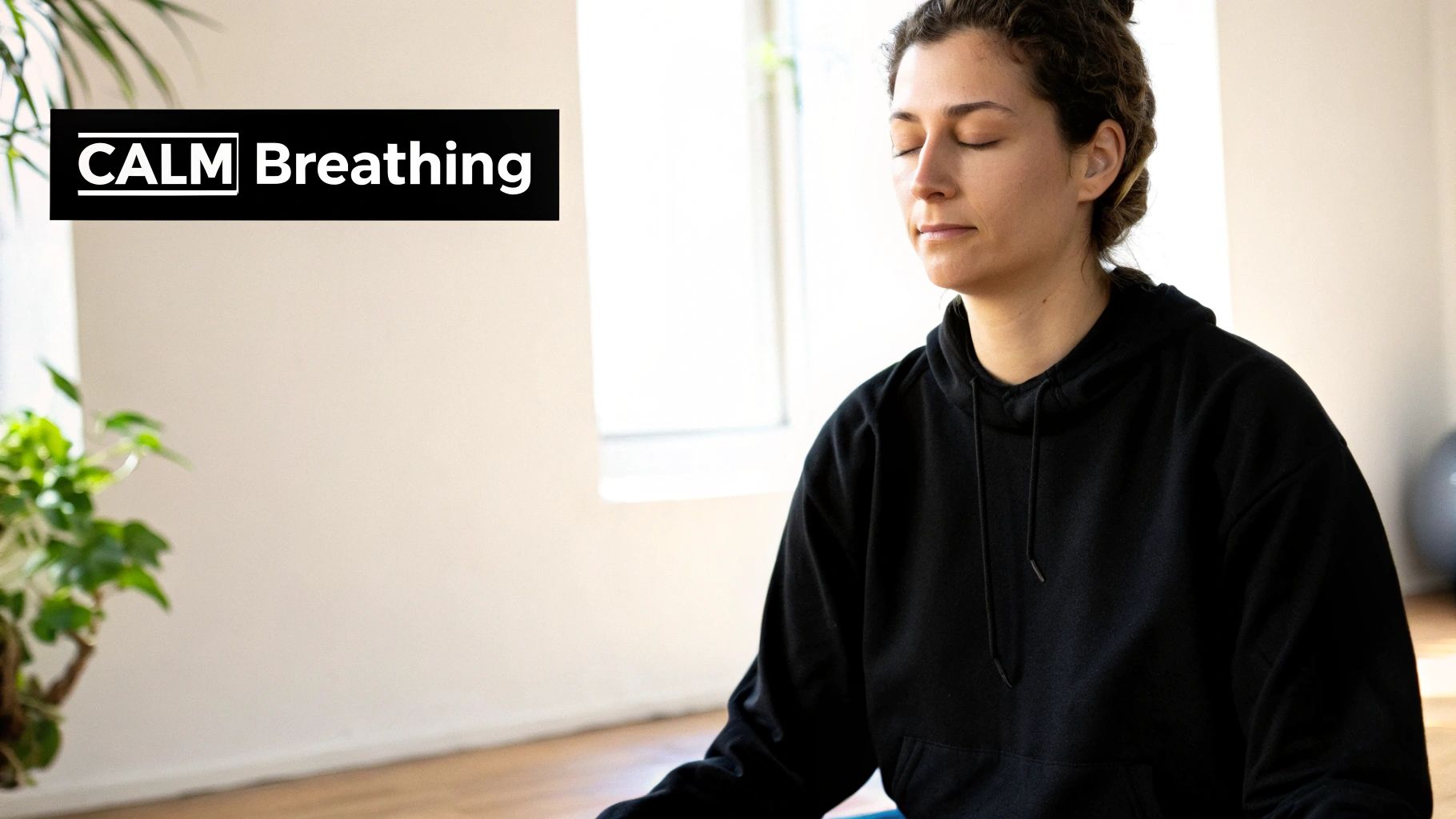 A woman in a black hoodie with closed eyes practicing calm breathing.