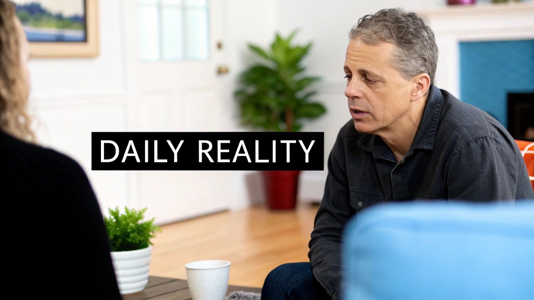 A man with gray hair in a dark shirt talks, sitting on a blue couch with 'DAILY REALITY' text.
