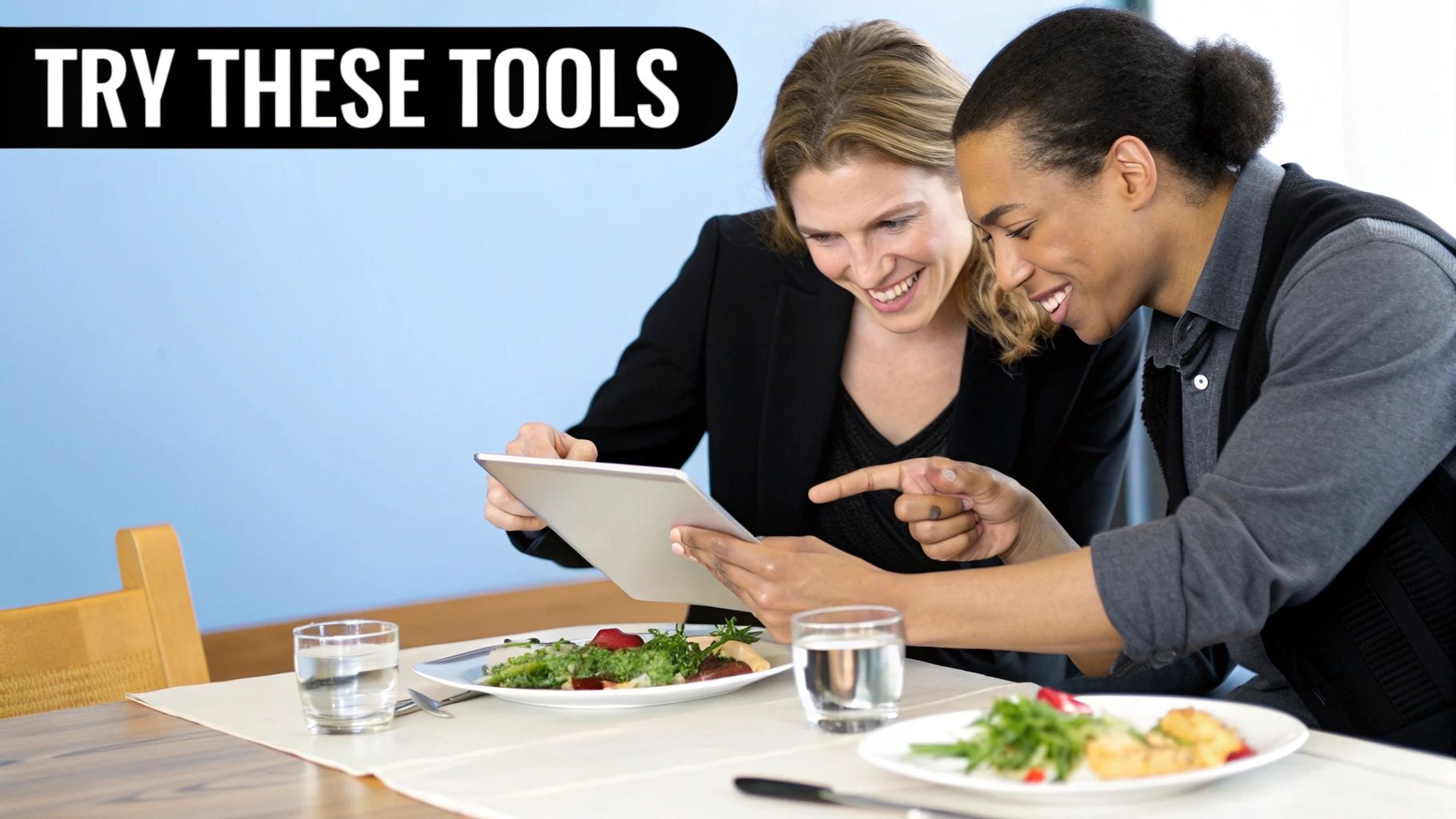 Two diverse individuals happily interacting with a digital tablet during a work lunch.