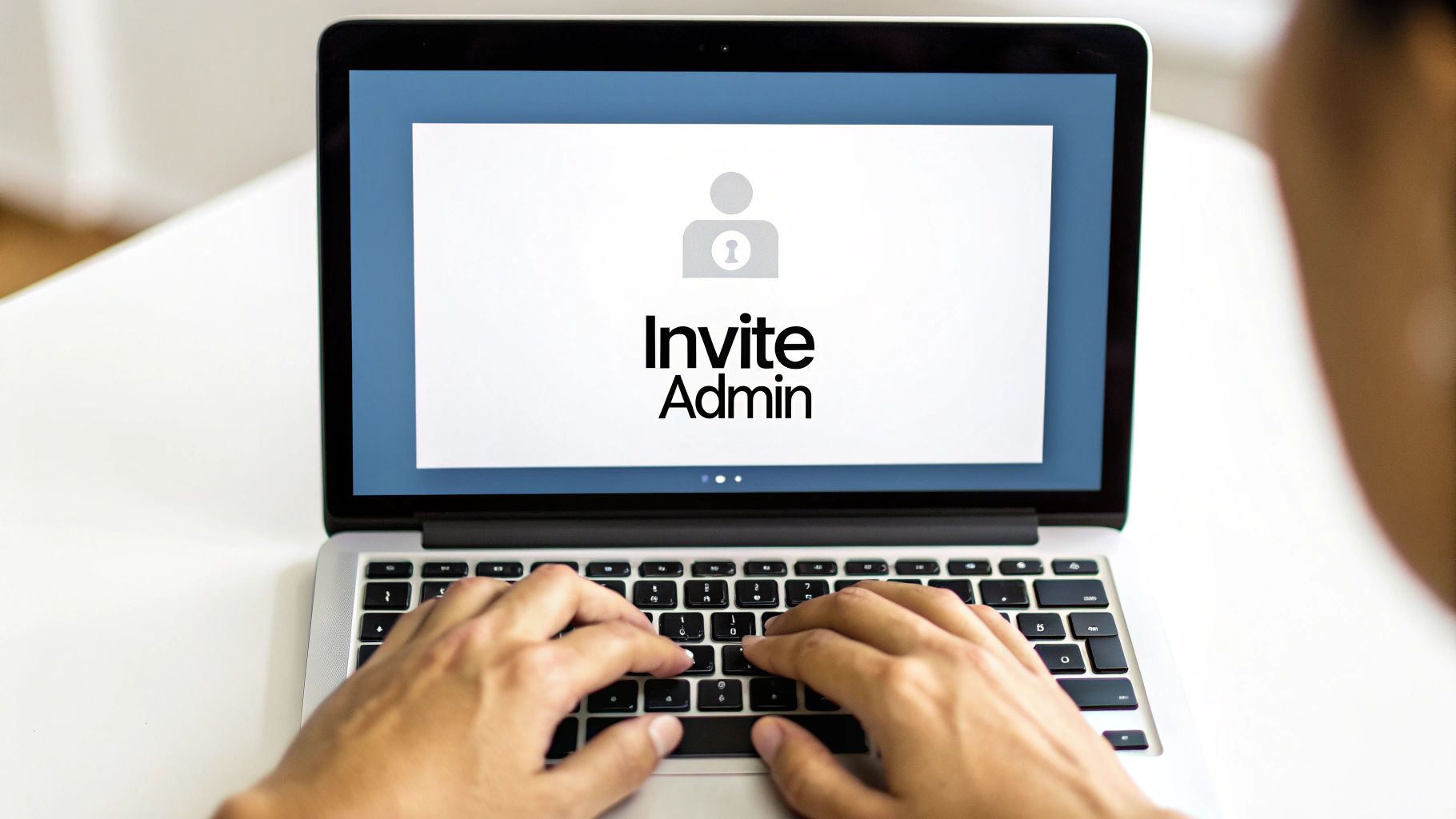 Close-up of hands typing on a laptop with an 'Invite Admin' screen visible.