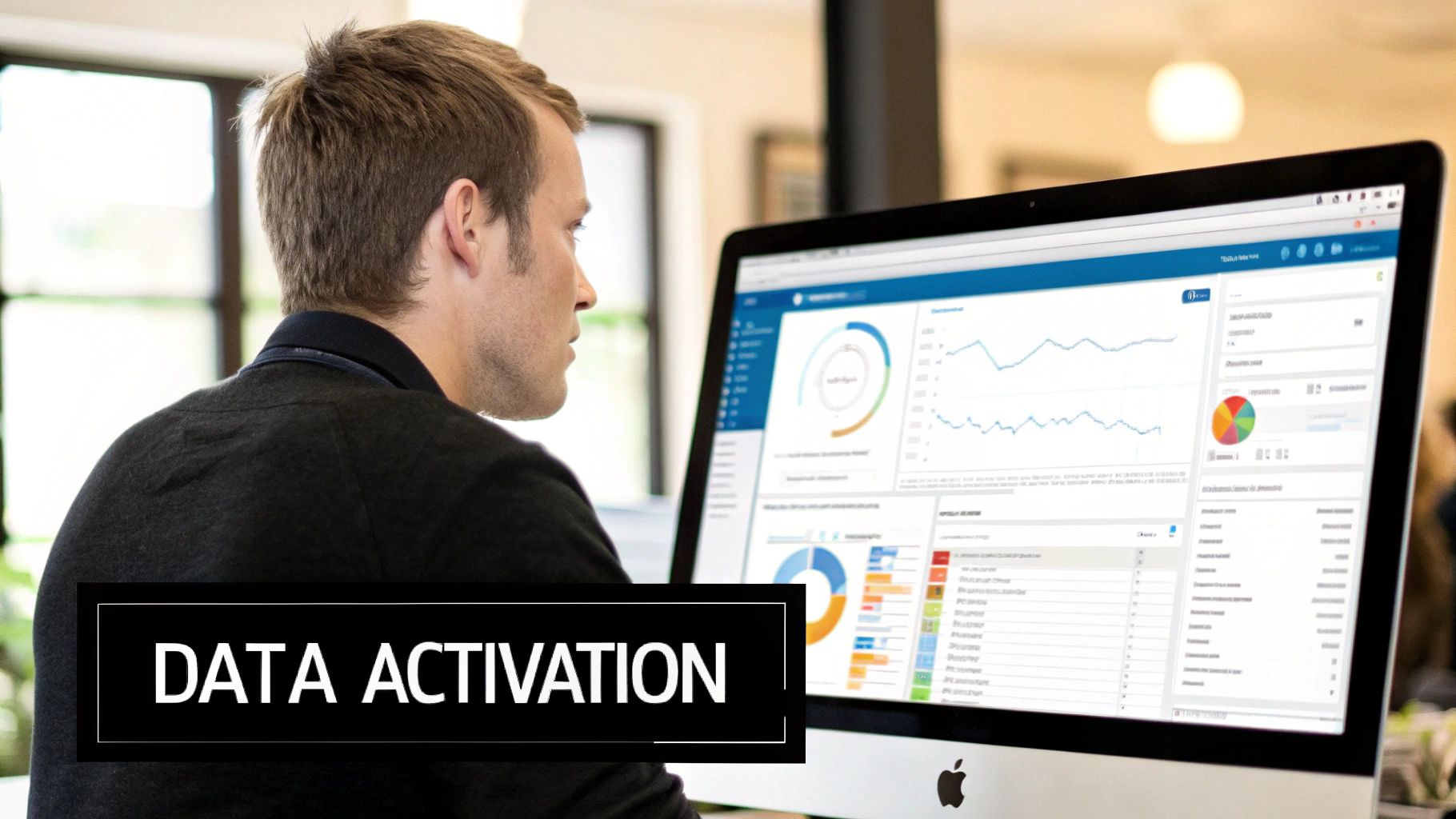 A man intensely analyzes data activation dashboards with charts and graphs on a computer monitor.