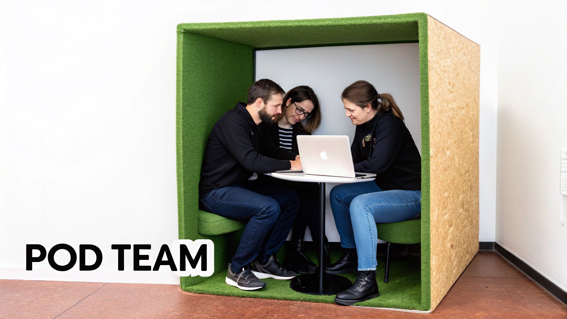 Three team members collaborate on a laptop inside a modern, green soundproof meeting pod.