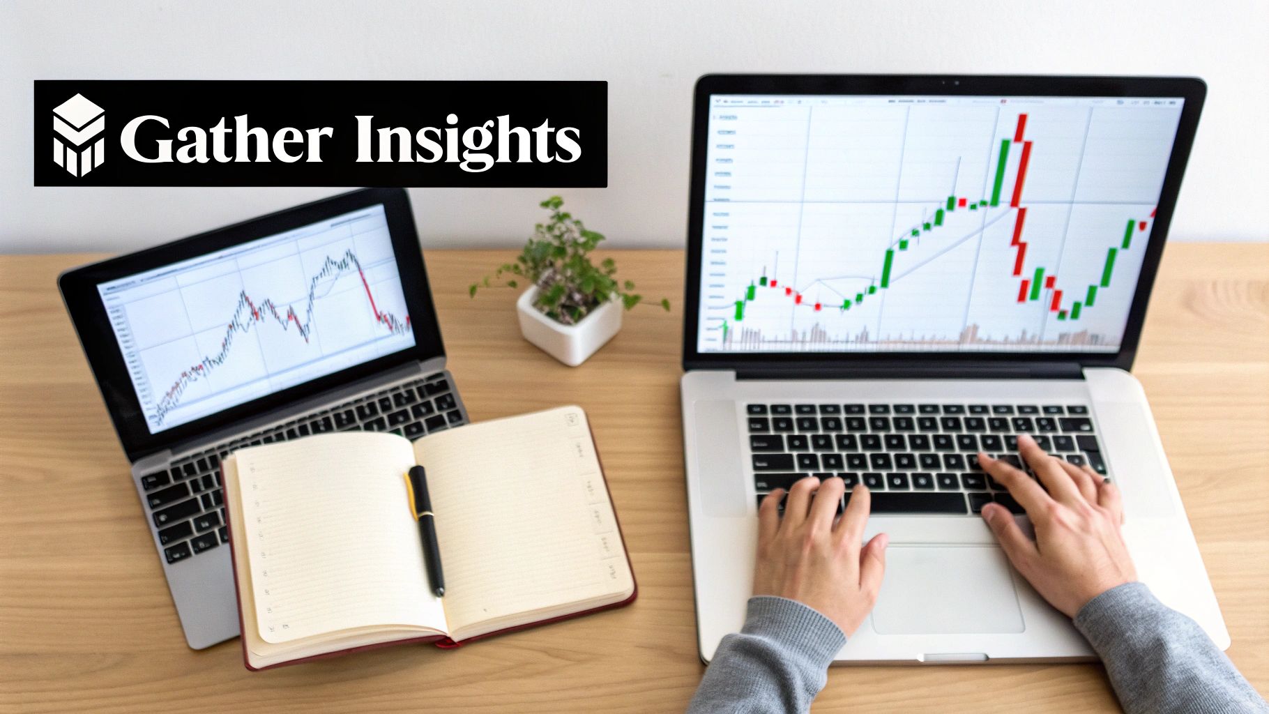 Hands typing on a laptop displaying stock charts, with another laptop, notebook, and plant on a desk.