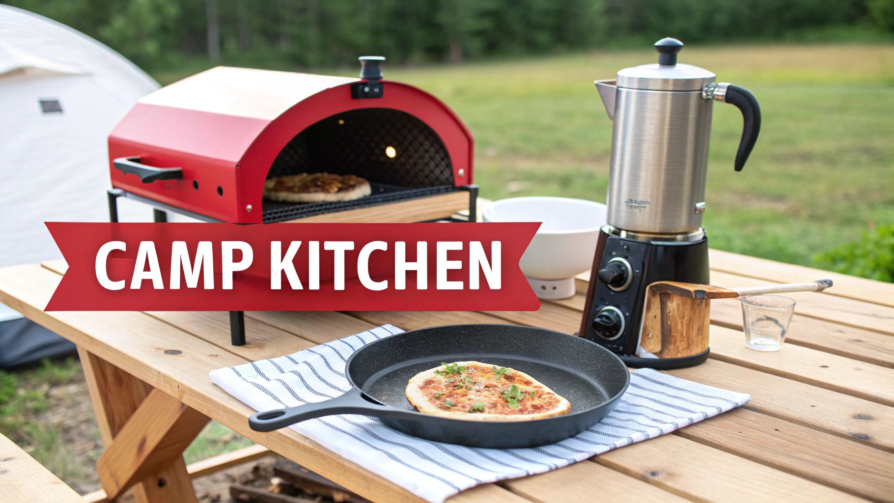 A vibrant red camp kitchen setup featuring a pizza oven, coffee maker, and skillet on a wooden picnic table outdoors.